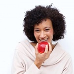 woman with dental implants in Bella Vista biting into a red apple 