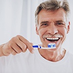 A man practicing dental implant care in Bella Vista by brushing his teeth