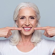 Senior woman pointing to whole healthy smile
