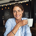 woman in a coffee shop holding a white mug 