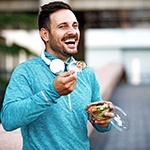 A man practicing dental implant care in Bella Vista by eating a salad