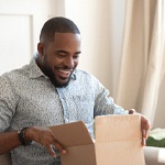 Smiling man sitting on couch and opening a package