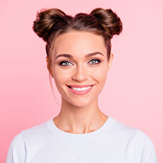 young woman smiling against pink background after getting teeth whitening in Bella Vista