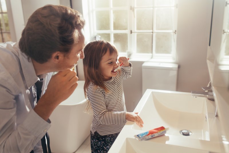 Father and daughter brushing teeth